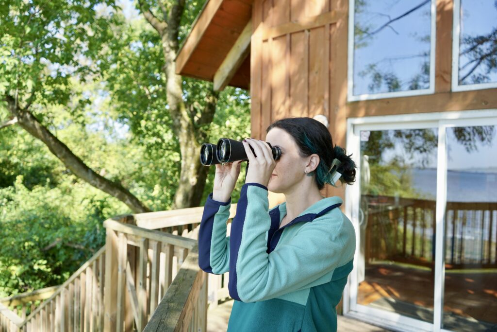 Women using binoculars outside of cabin.
